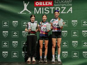 Powiększ obraz: Trzy zawodniczki na podium podczas ceremonii dekoracji na tle baneru ORLEN Szukamy Następcy Mistrza