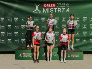Powiększ obraz: Szóstka młodych skoczków narciarskich na podium z medalami i dyplomami podczas dekoracji zwycięzców